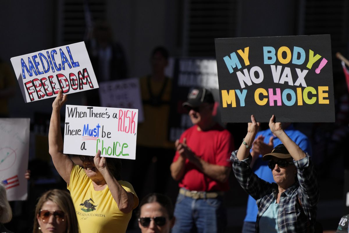 People hold signs as several hundred anti-mandate demonstrators rallied last month outside the Florida Capitol during a special legislative session considering bills targeting COVID-19 vaccine mandates,