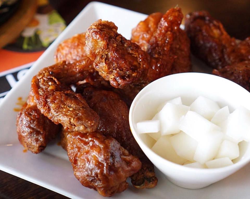 A white, square plate piled with crispy glazed chicken drummies.