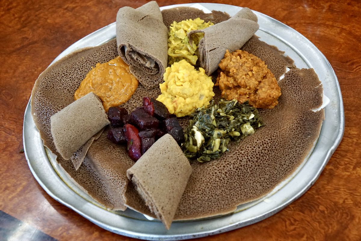 A platter of injera and vegetable dishes on a wooden table at Ranch Side Cafe.