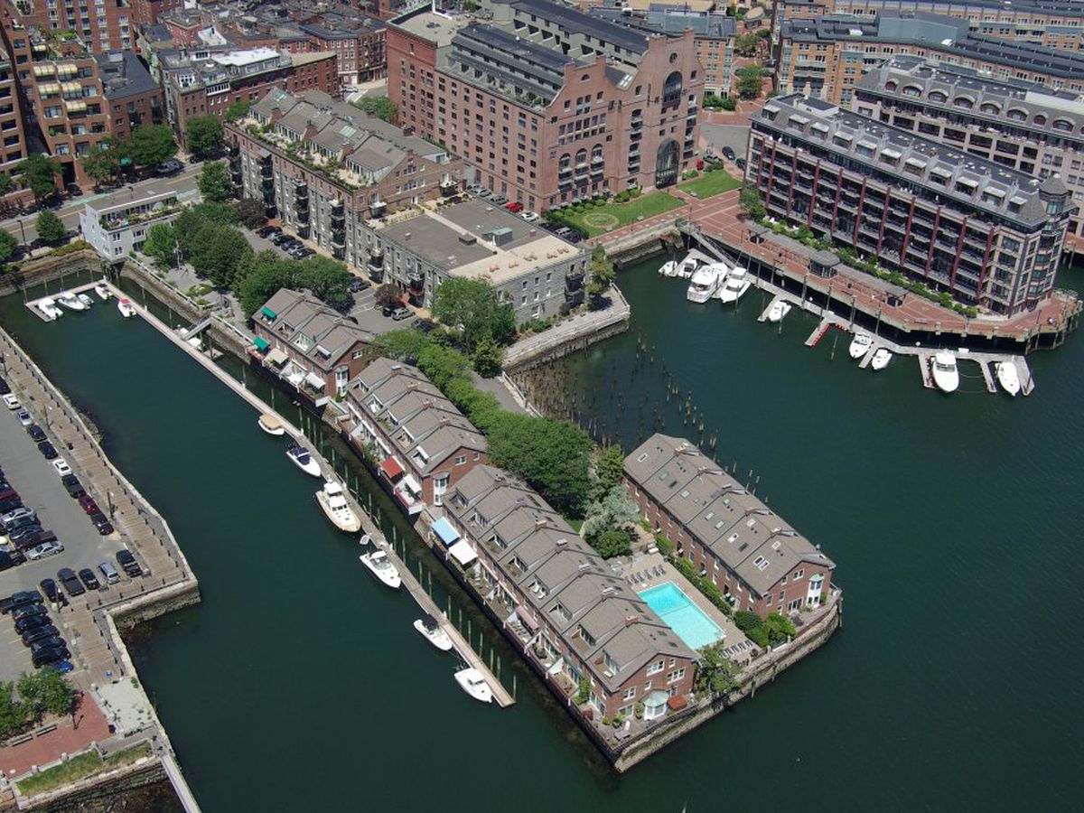 An aerial view of a waterfront. One of the piers has a swimming pool on it.