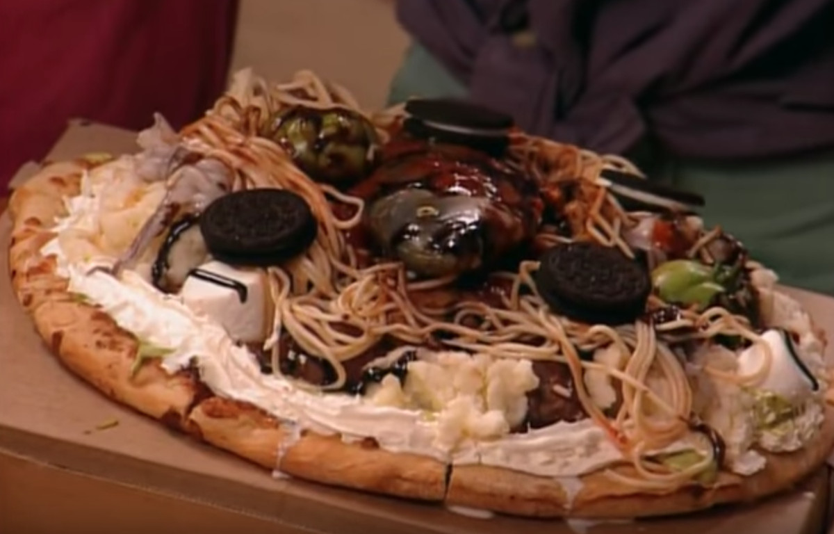 A pizza topped with whipped cream, guacamole, Oreos, spaghetti, and many other ingredients