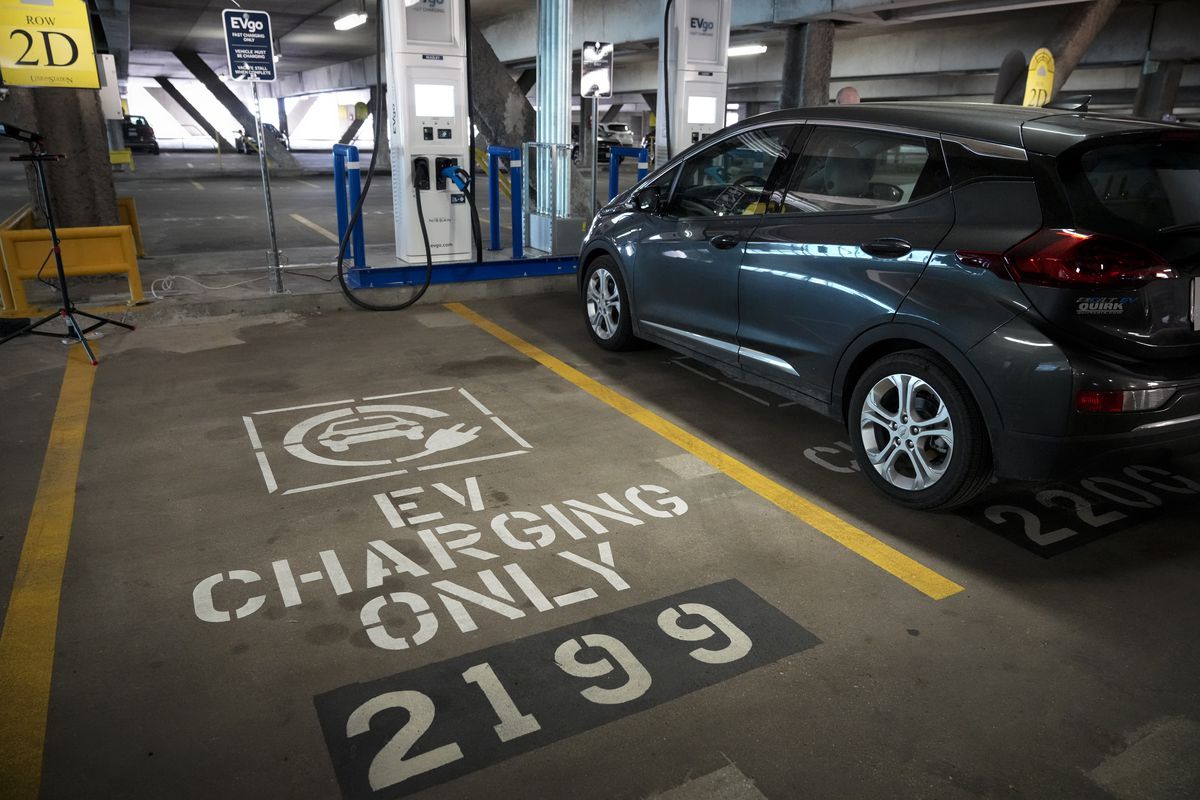 Електрическо превозно средство се зарежда в гараж до паркомясто, запазено за EV зареждане.