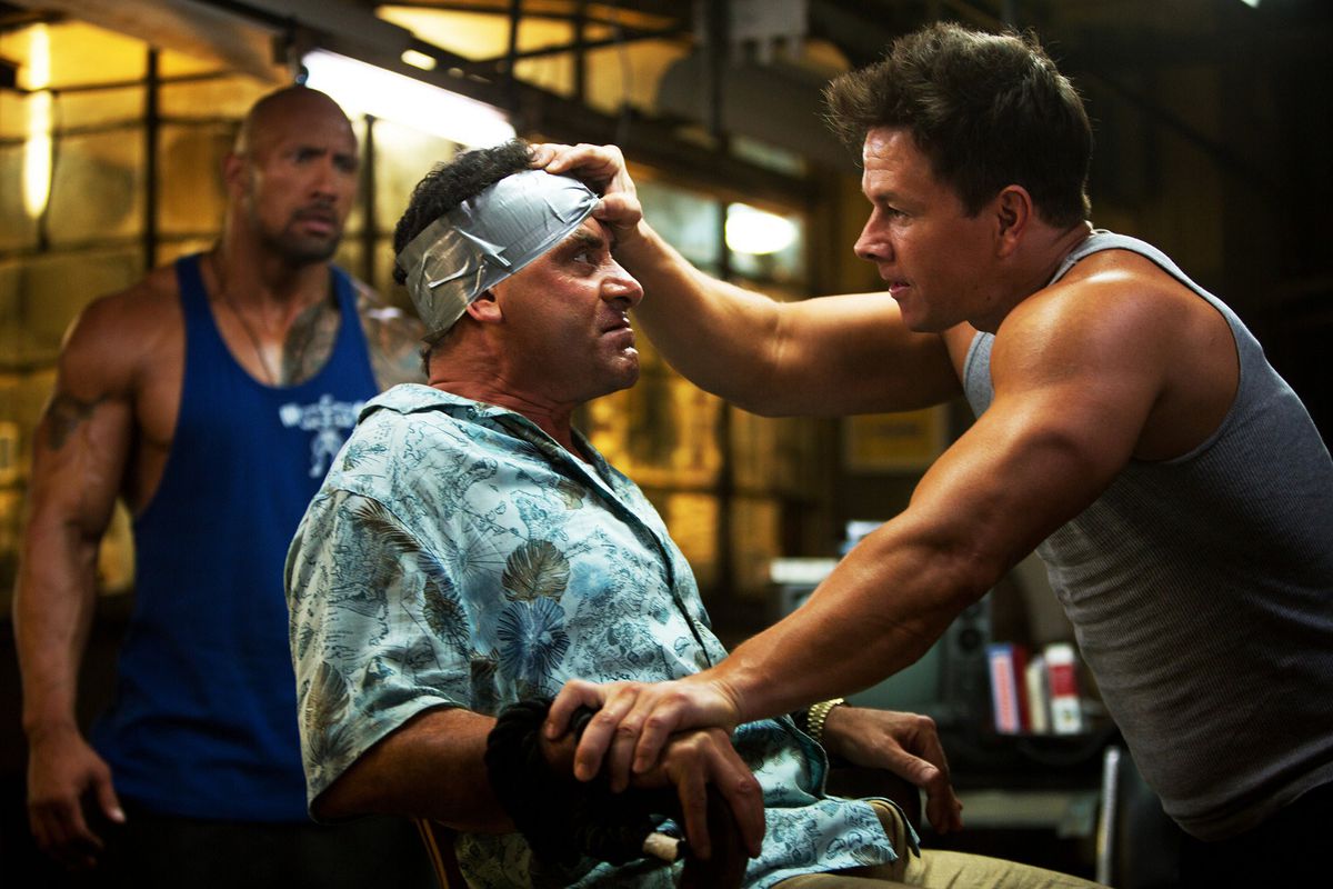 Mark Wahlberg and Dwayne Johnson observe a kidnapped Tony Shalhoub in Pain &amp; Gain.