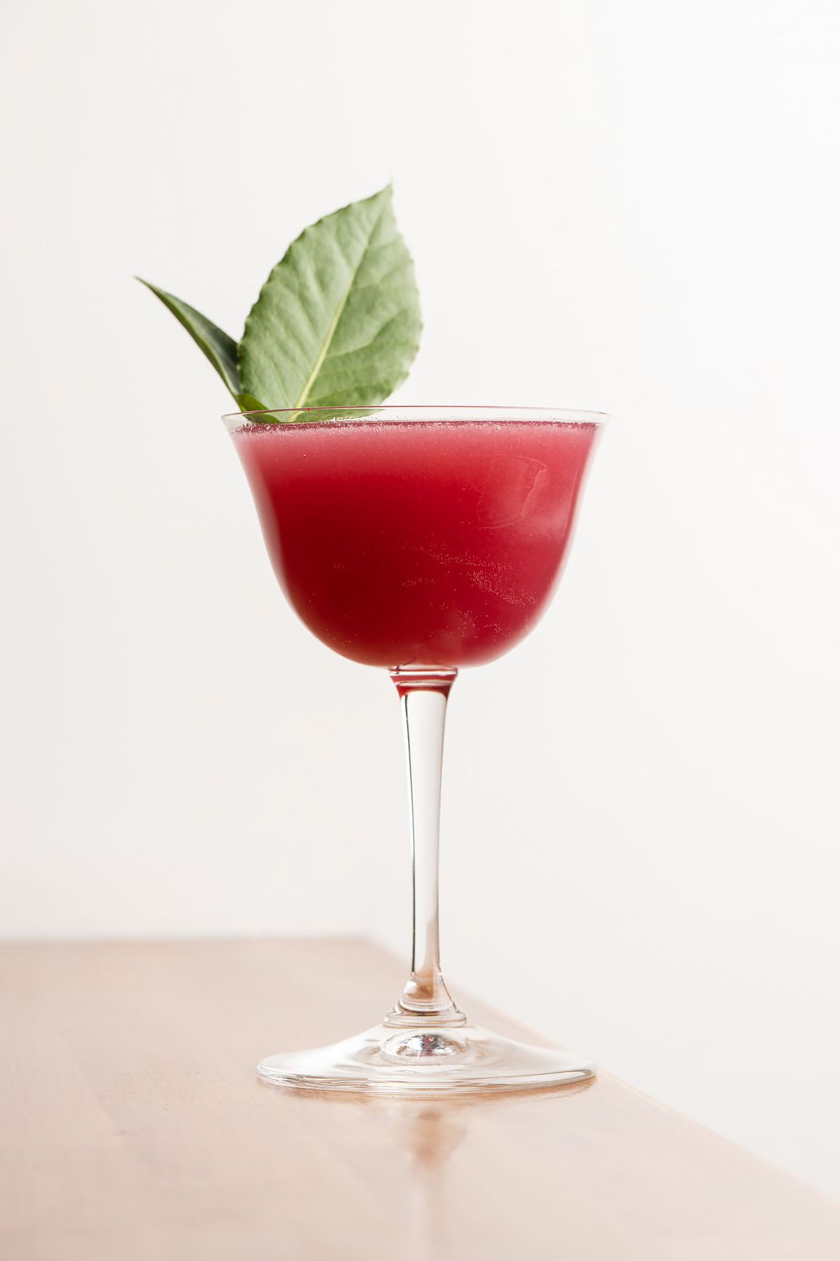 A purple cocktail with a shiso leaf.