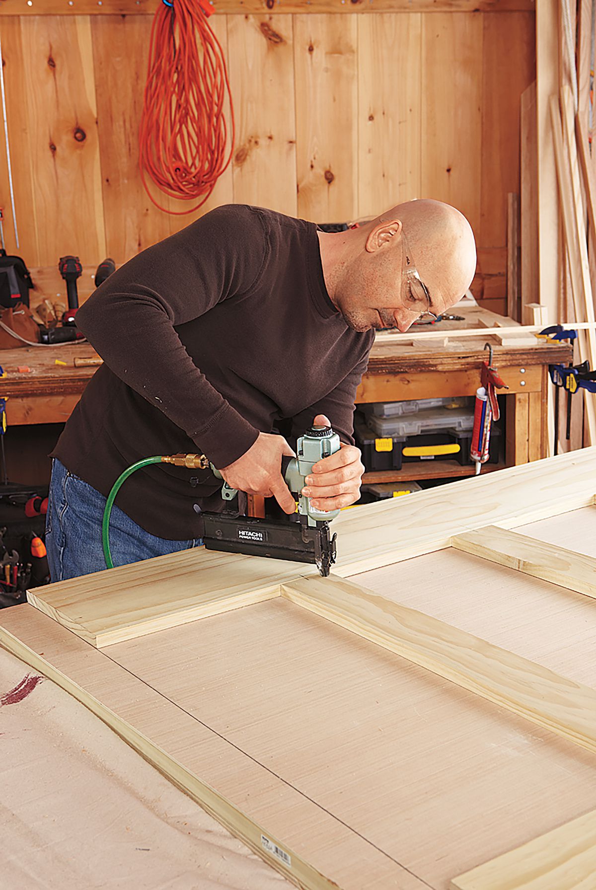 Man Nailing Stiles And Rails To Front Panel Of DIY Bar