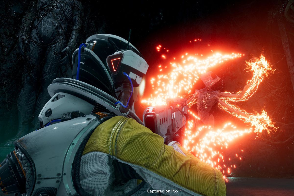 a close-up from behind a character in a spacesuit firing an energy weapon at an alien in Returnal