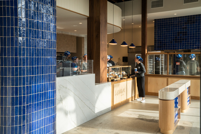 A wood counter and bakery case made of blue tile and marble at Levain Bakery.