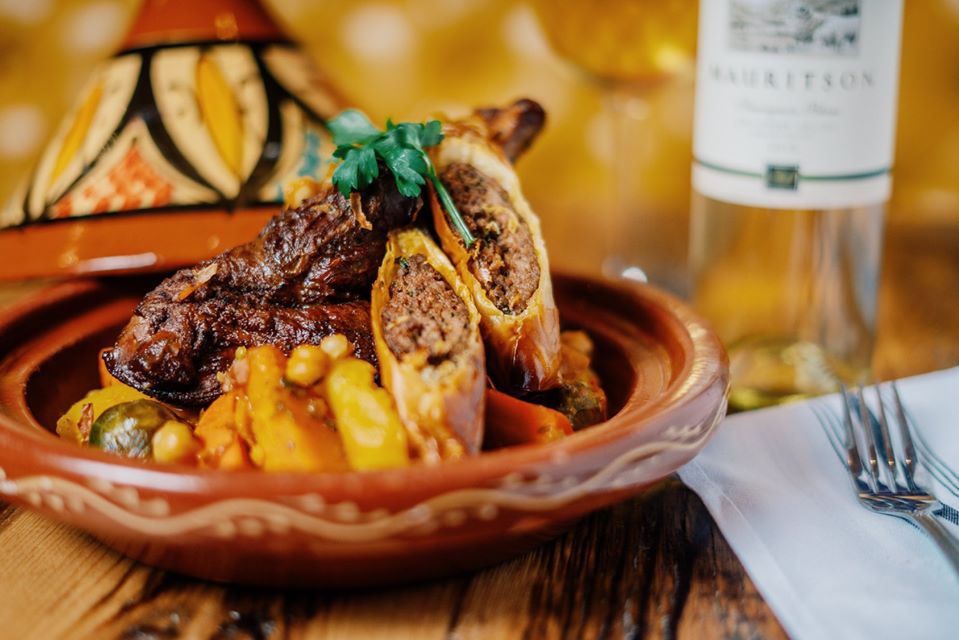 A Moroccan lamb dish is served in a decorative brown bowl