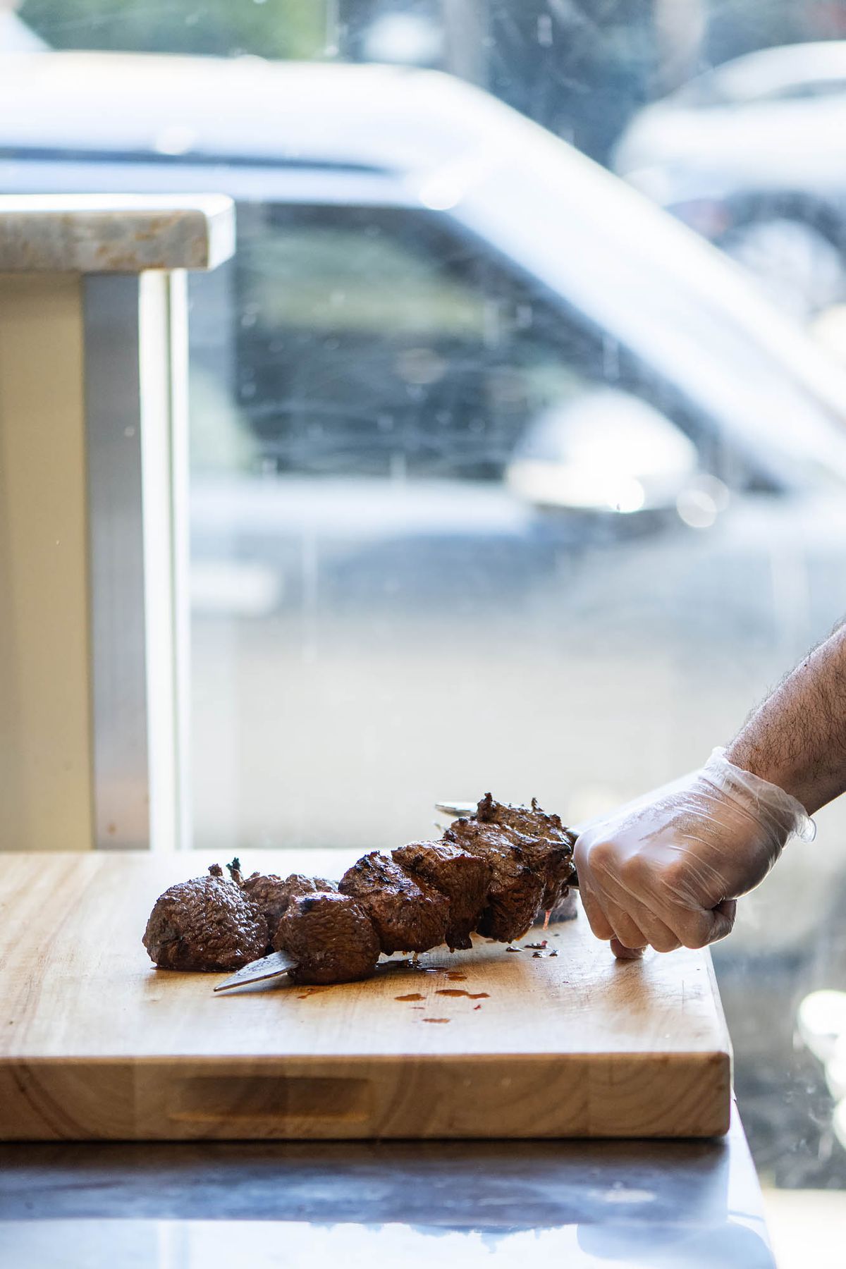 A man prepares grilled meat next to an open window at MidEast Tacos in Silver Lake, California.