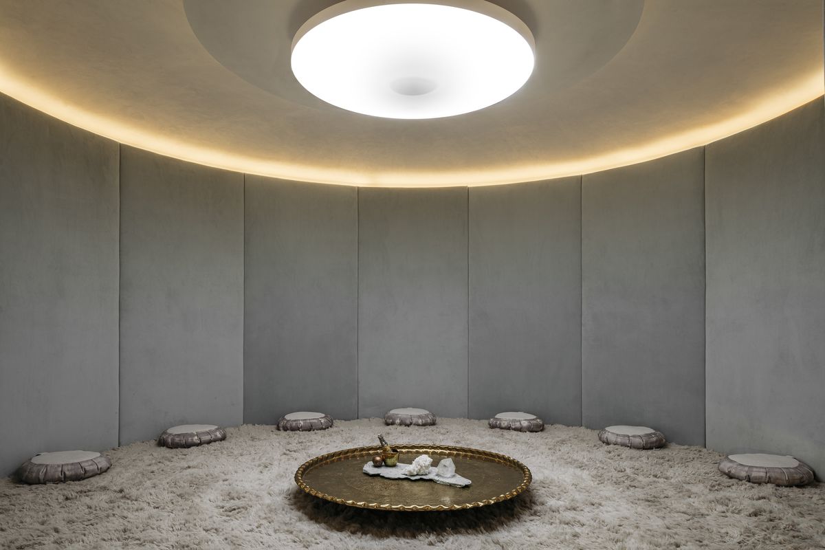 A curved meditation room featuring white and grey walls and backlighting.