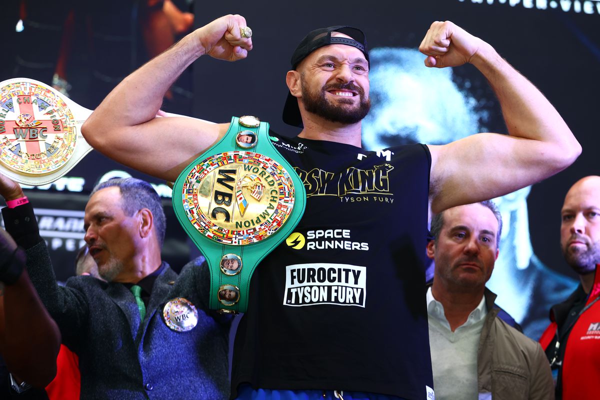 Tyson Fury flexes on the scale during the weigh in with Dillian Whyte prior to their WBC heavyweight championship fight at BOXPARK on April 22, 2022 in London, England.