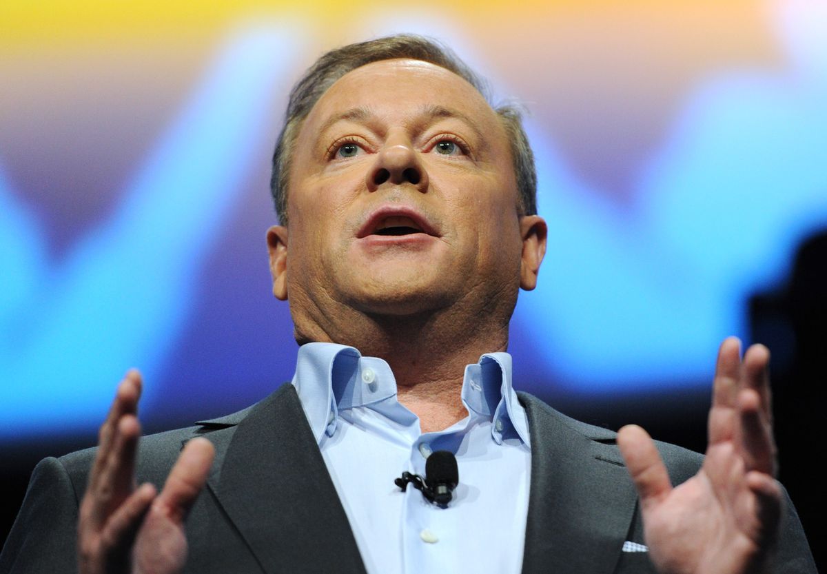 a close-up of Jack Tretton, a middle-aged man in a light blue dress shirt and dark gray jacket, speaking at Sony’s E3 2013 PlayStation press conference