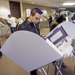 David Gonzalez, center, votes at the Salt Lake County Government Center Tuesday, Nov. 8, 2016, in Salt lake City. Utah's mostly Mormon, mostly Republican voters are going to the polls Tuesday to determine if the GOP's five-decade winning streak in presidential elections will remain intact or be snapped. (AP Photo/Rick Bowmer)