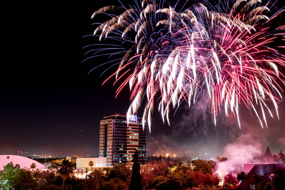 White, red, and purple fireworks exploding over San Jose.