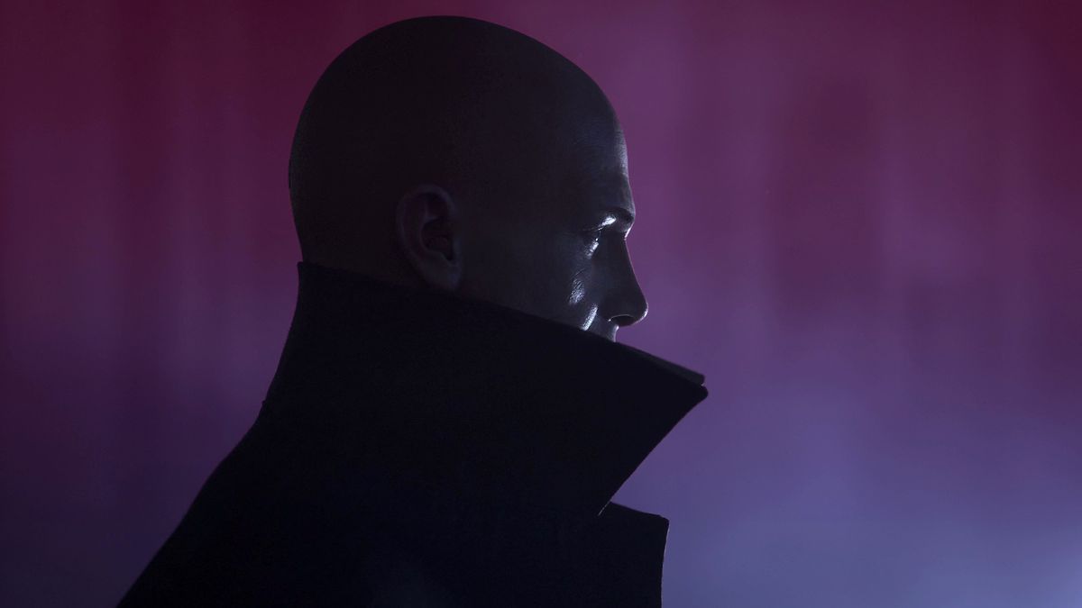 Profile image of bald man against a dark purple tinged background