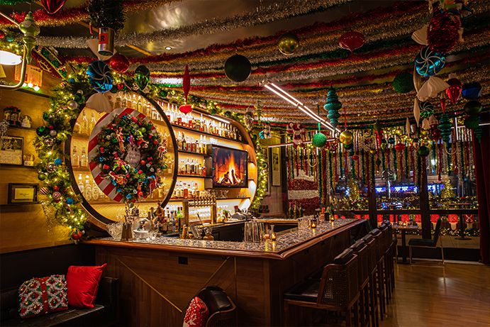 The bar is packed with tinsel, wreaths, ornaments, lights, giant candies and themed throw pillows.