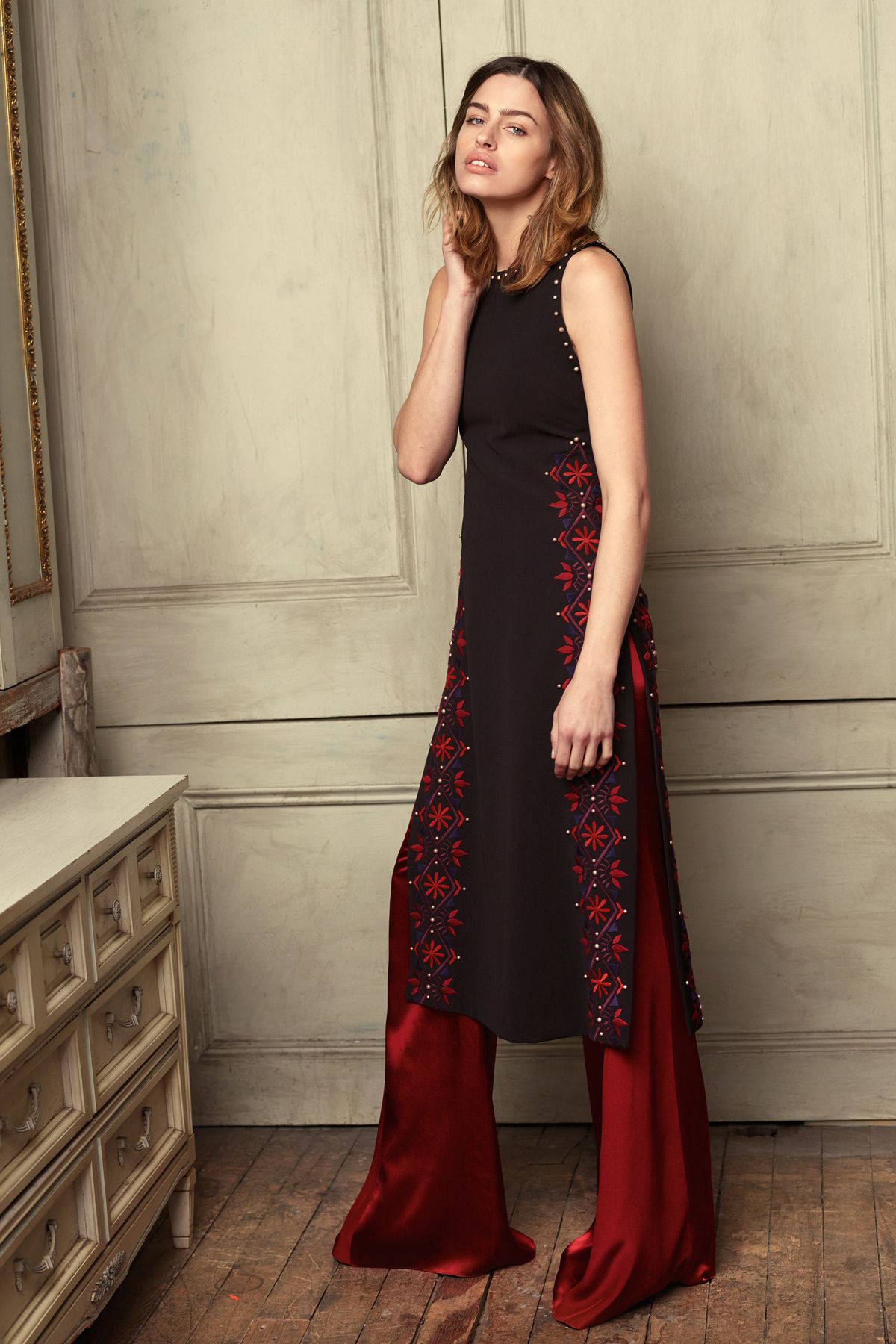 A model wearing red pants and a black sleeveless dress