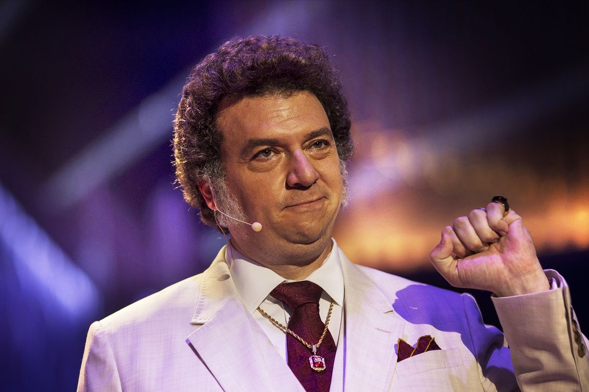 Jesse Gemstone (Danny McBride), wearing a white suit and sporting thick mutton chops, holds up his fist in The Righteous Gemstones