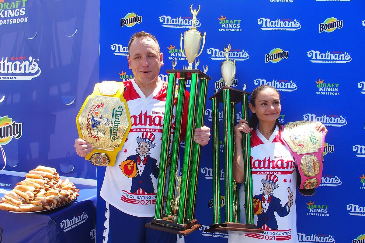 Winners Joey Chestnut and Michelle Lesco pose with their championship belts and trophies at the 2021 Nathan’s Famous International Hot Dog Eating Contest at Coney Island on July 4, 2021 in New York City.