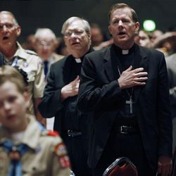 Bishop John C. Wester of the Salt Lake Diocese of the Catholic Church pledges allegiance to the flag along with hundreds of Boy Scouts at a banquet marking the 100th anniversary of the Boy Scouts of America at the Salt Palace on Thursday.  