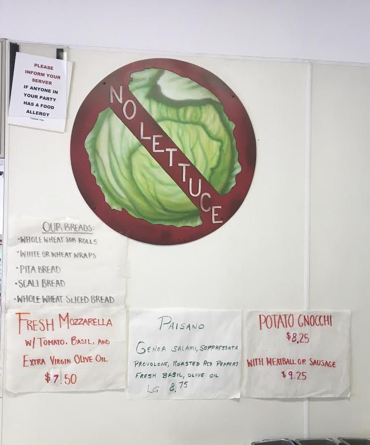 A sign with a crossed out lettuce painted on the front to indicate that “no lettuce” is permitted on any of the sub shop’s sandwiches