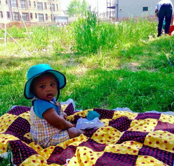 Martha Itulya-Omollo’s baby enjoys an afternoon at a Woodlawn community garden. | Photo provided by 65th &amp; Woodlawn Garden Committee