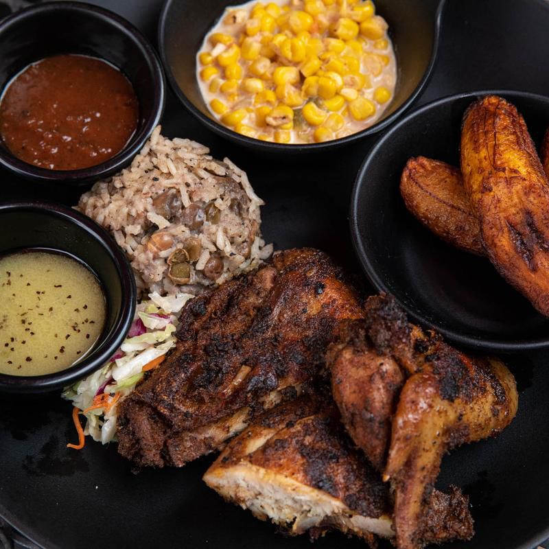 Jerk chicken plate with corn and fried plantains.