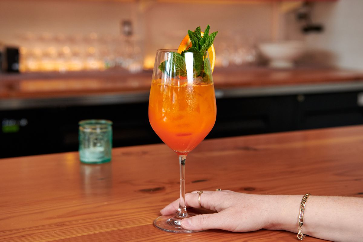 An orange-hued cocktail in a wine glass at Dame. 