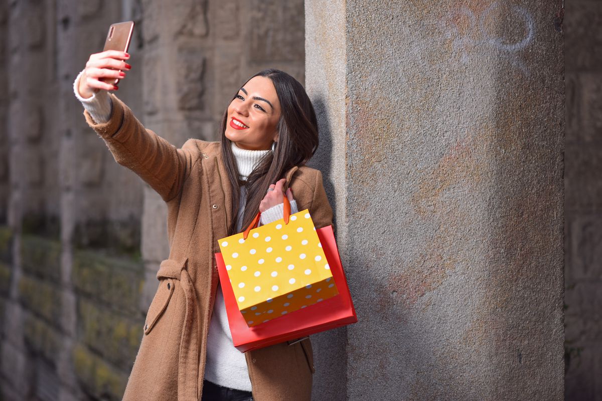 Woman taking a selfie with shopping bags.
