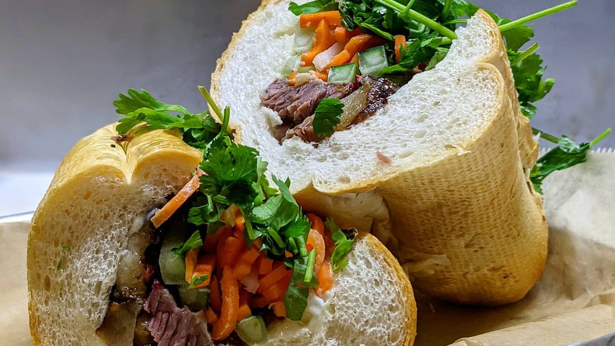 Beef brisket banh mi with shredded carrots, cucumbers, topped with cilantro stuffed into a crunch baguette and cut in half from Pho Cue in Atlanta