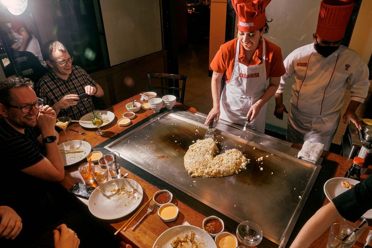 Jaya shapes rice into a heart on the griddle as her smiling friends watch.