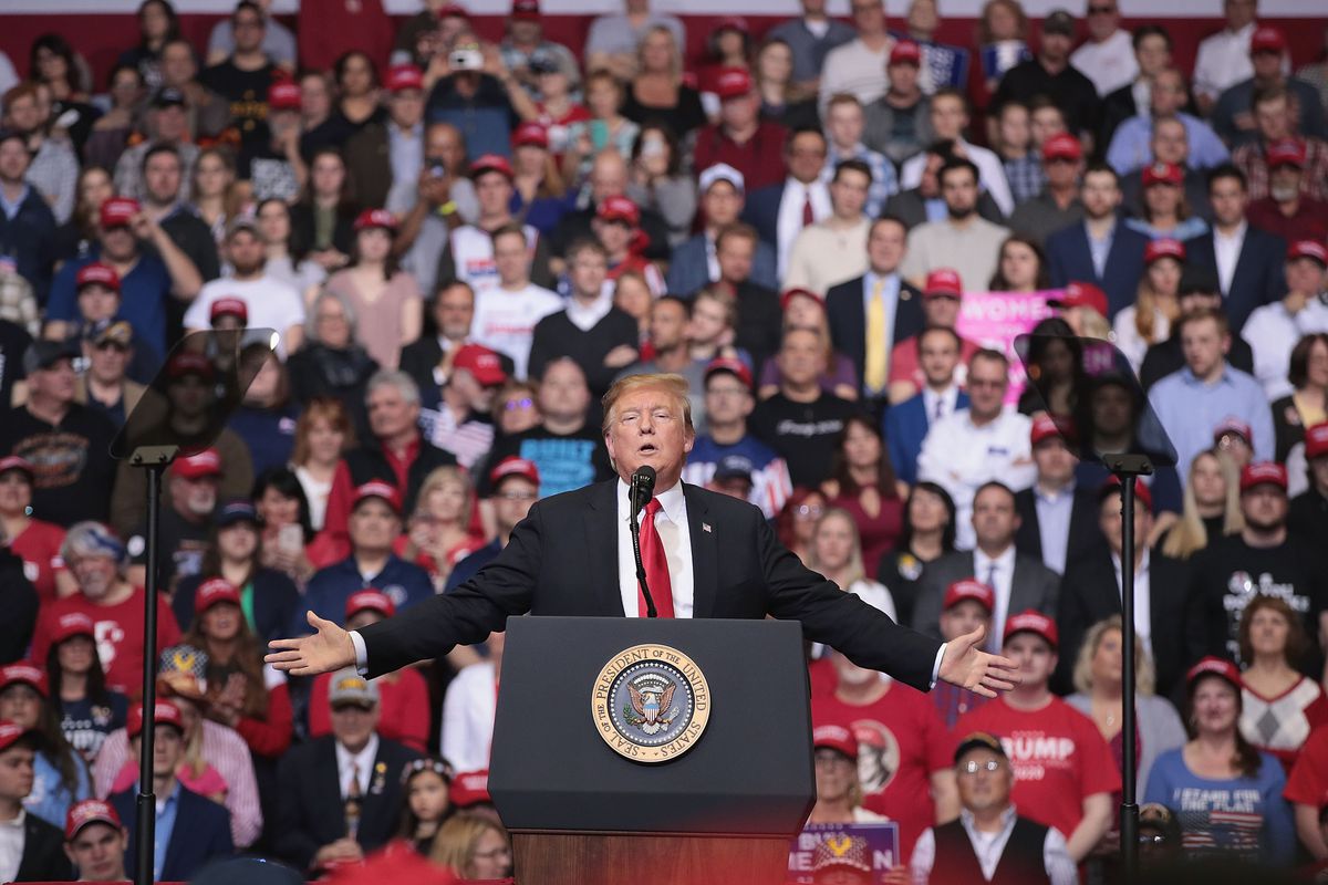 President Donald Trump stands a podium at a rally.
