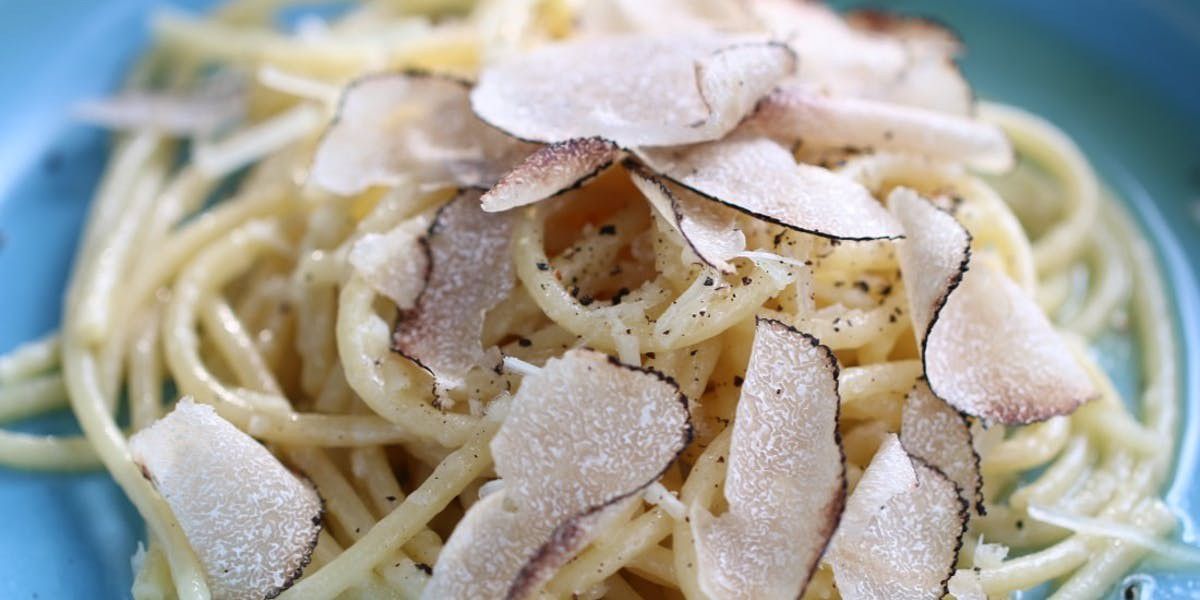 A bowl of pasta topped with shaved truffles