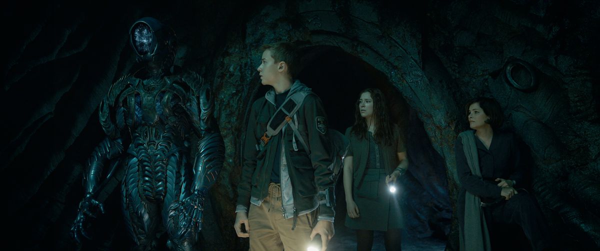 (L to R) Brian Steele as Robot, Maxwell Jenkins as Will Robinson, Mina Sundwall as Penny Robinson, Parker Posey as Doctor Smith in episode 302 of Lost In Space.