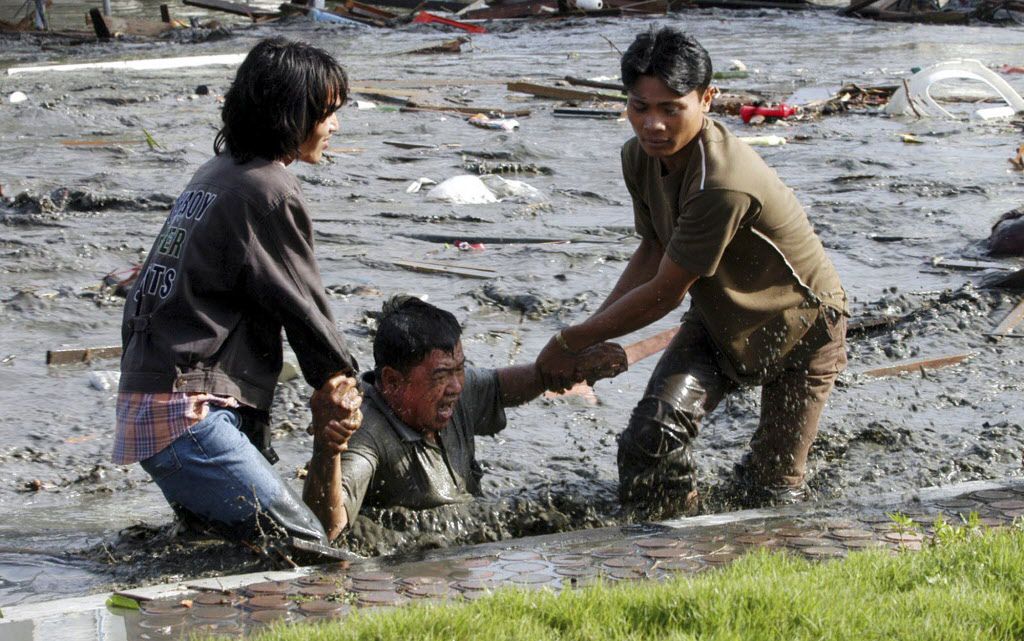 <small>In this Dec. 26, 2004 file photo, Acehnese youths try to pull a man to higher ground through a flooded street a moment after tsunami strike in the provincial capital of Banda Aceh, Aceh province, Indonesia. | Bedu Saini / AP</small>