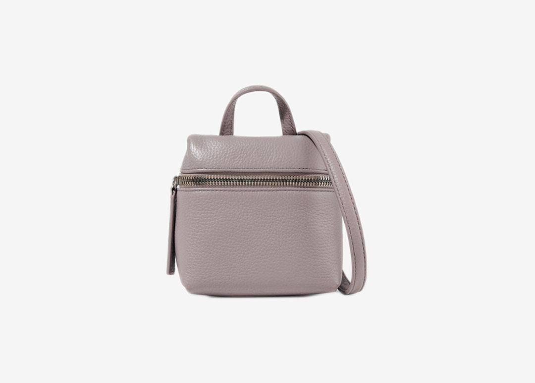 Pale lilac cube crossbody bag with top handle and front zipper. 