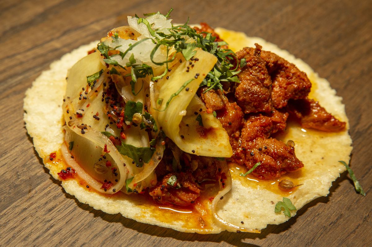 A taco with meat and toppings.