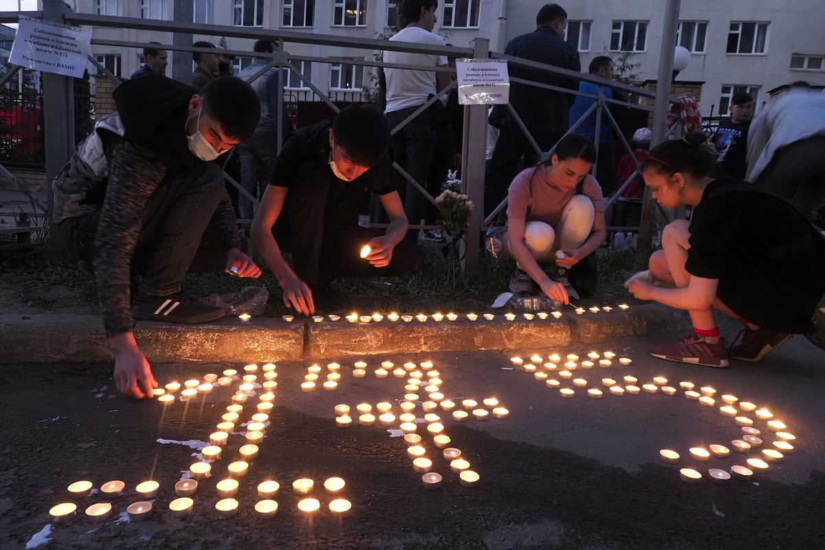 People place lit candles on the ground to form the number 175 after a shooting at school No.175 in Kazan, Russia, Tuesday, May 11, 2021.