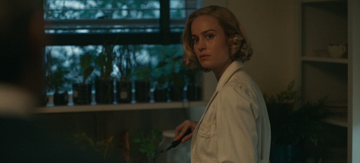 Elizabeth (Brie Larson) standing and watering a plant while turning and looking incredulous