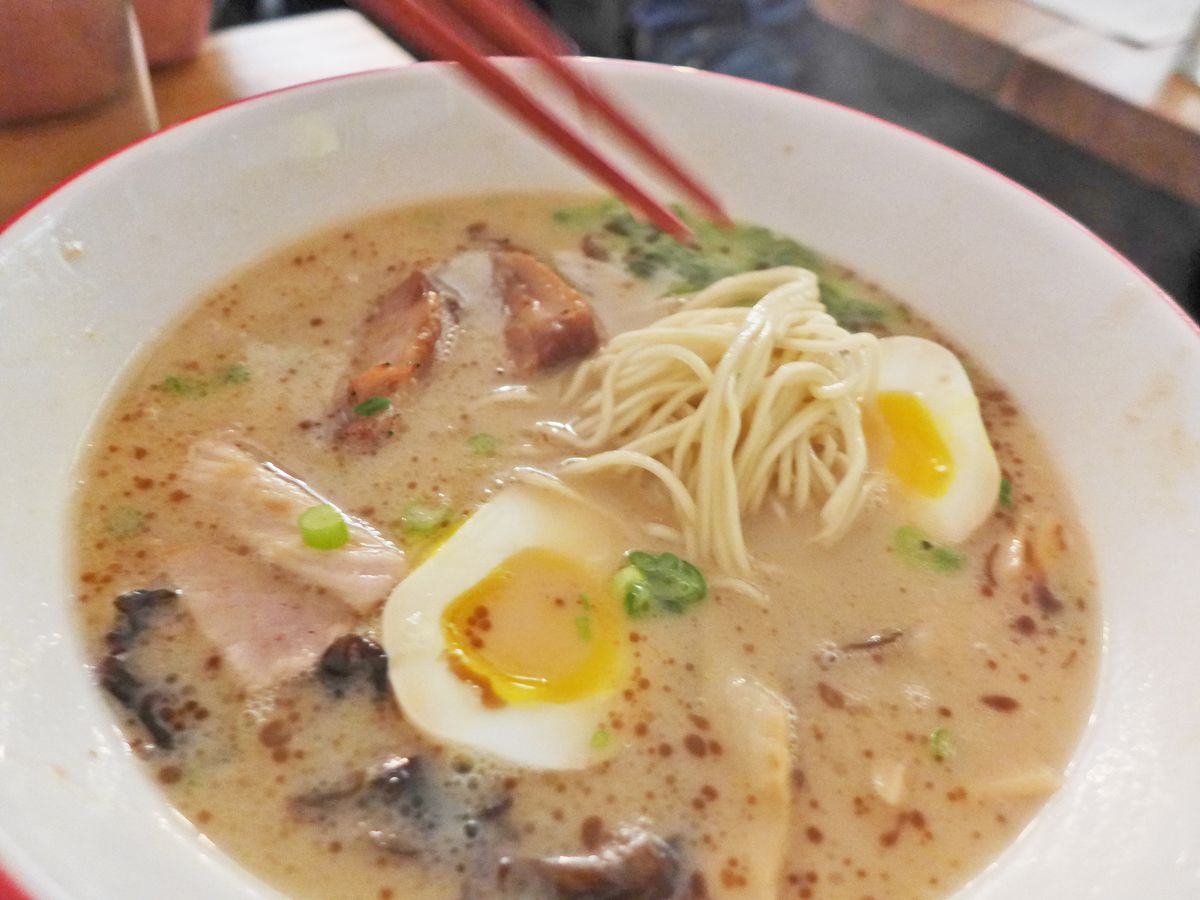 A milky beige broth with oil droplets on its surface, with noodles and boiled eggs to be seen.