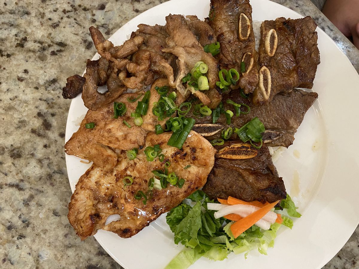 A plate of ribs and other meats with salad. 