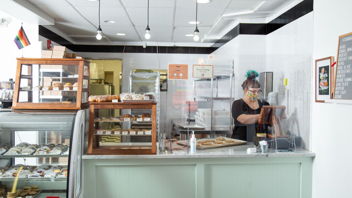 The pastry case and counter at Crust vegan bakery with a woman workin behind the counter and baked goods in the case