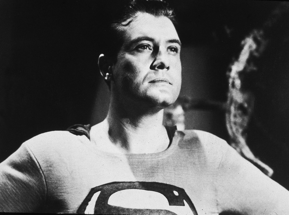 A black and white portrait photo of George Reeves as Superman, as he looks into the distance in that serene Superman way. 