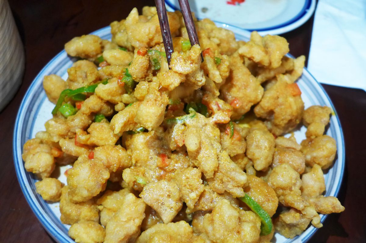 A heap of fried chicken morsels in a blue rimmed bowl.
