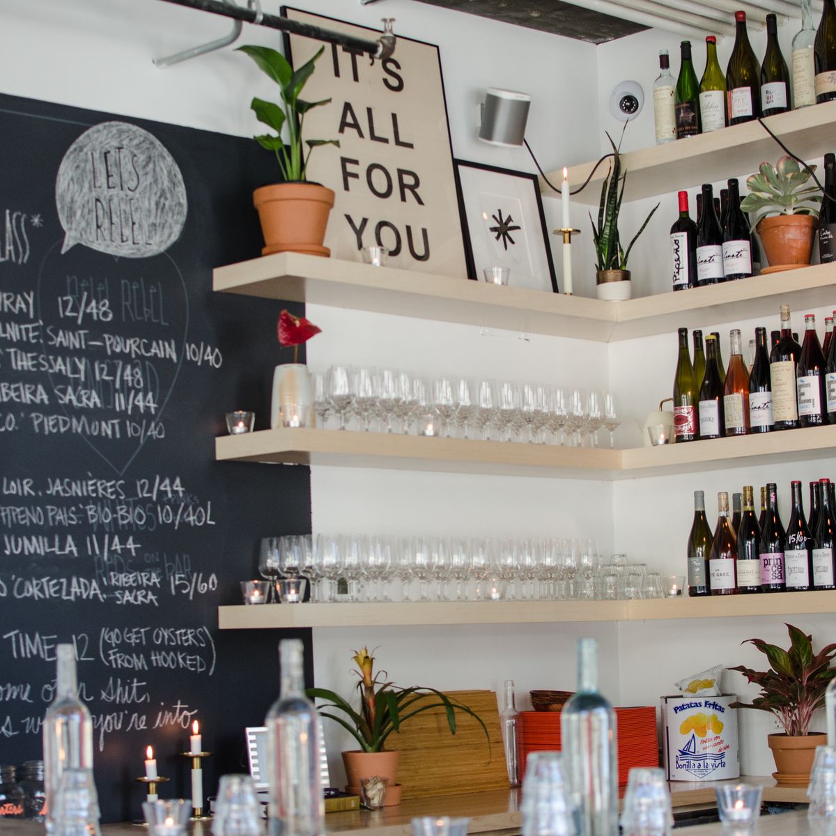 Shelves of wine bottles and a chalkboard menu inside a wine bar