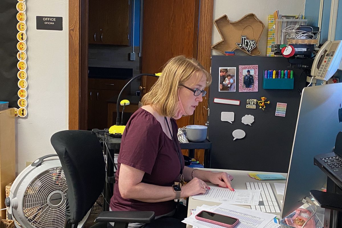 A teacher at her computer in a classroom.
