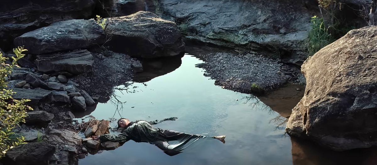 A Native woman’s corpse lies in a small pool between rocks and a gravel wash in a scene from Martin Scorsese’s Killers of the Flower Moon