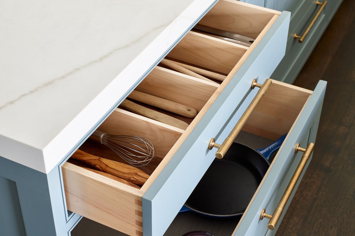 A detailed shot of open drawers. The top drawer has dividers for large cooking utensils and the bottom drawer holds pots and pans. 
