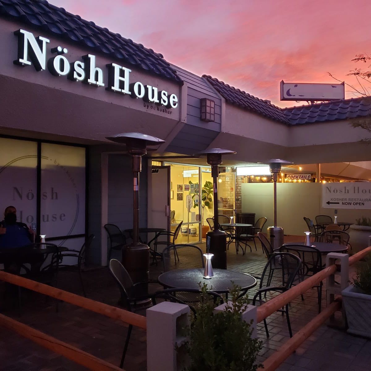 A small strip mall patio for a restaurant during a blazing sunset.