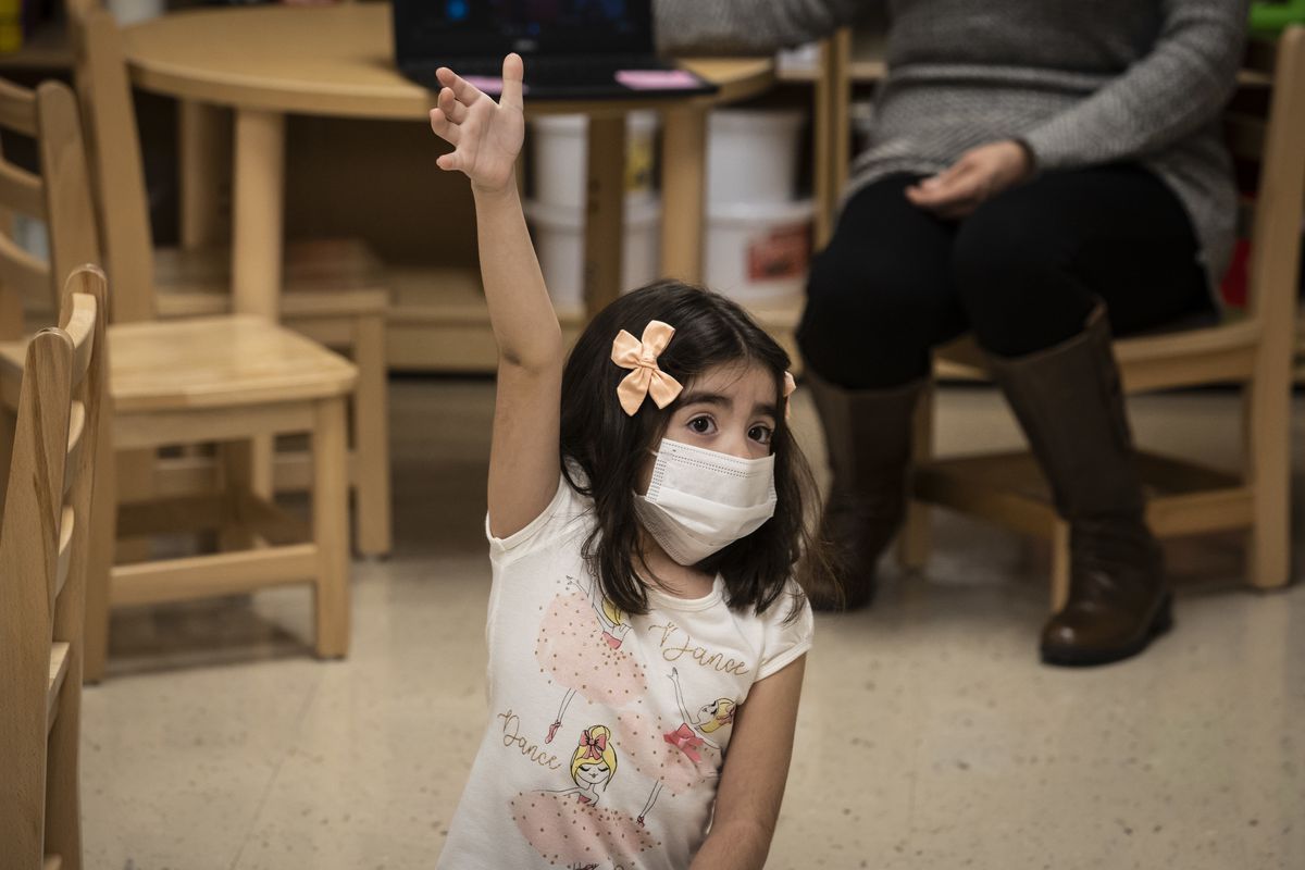 A preschool student raises her hand during class at Dawes Elementary School on the Southwest Side.